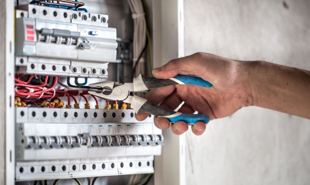 Electrician Bayside working on a switchboard in Bayside using insulated pliars